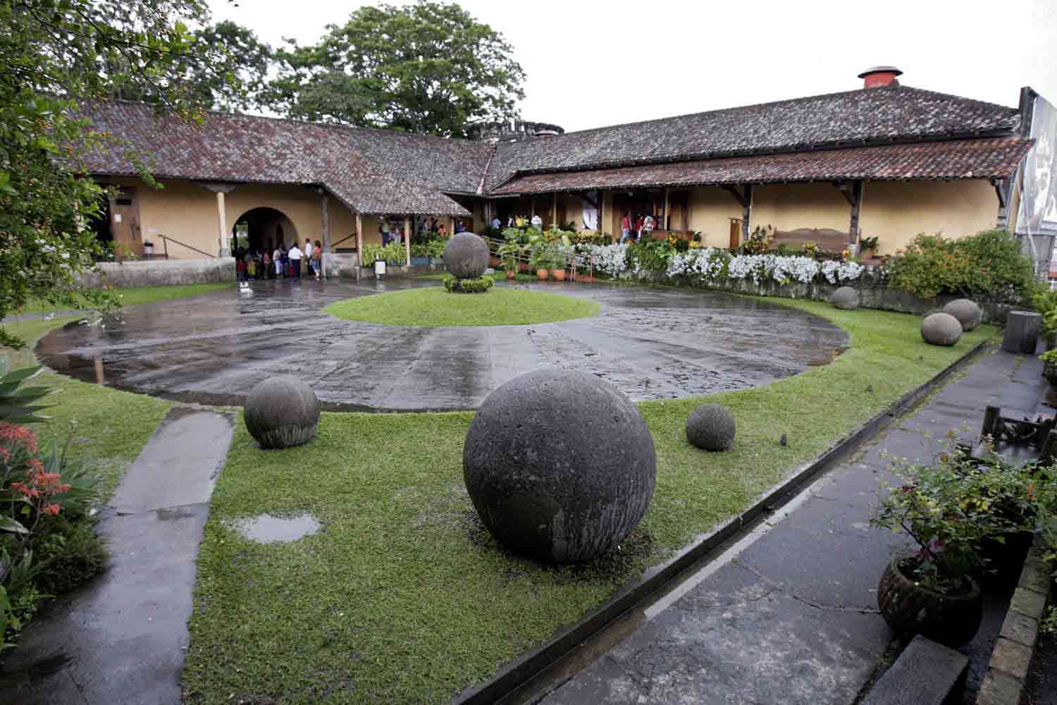 Several stone spheres of different sizes are on the grounds of a building.