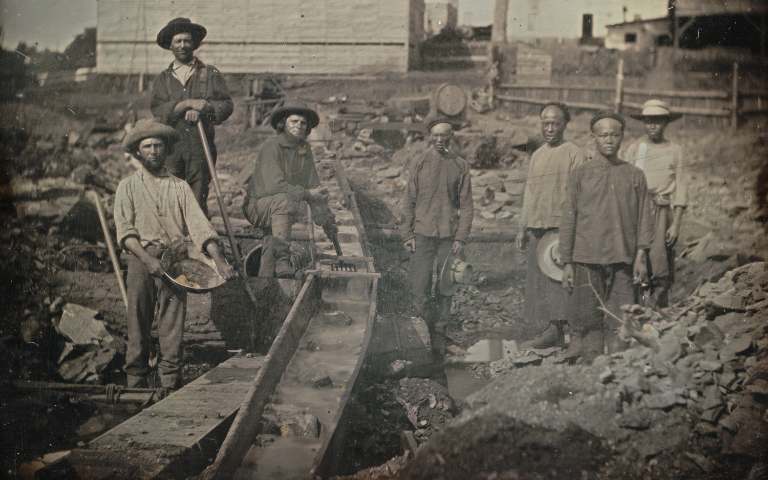 White and Chinese workers pose for a photo at a gold mining site.