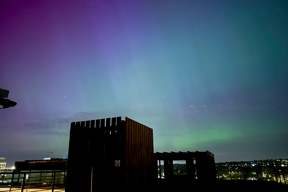 A building against a purple, green, and blue night sky