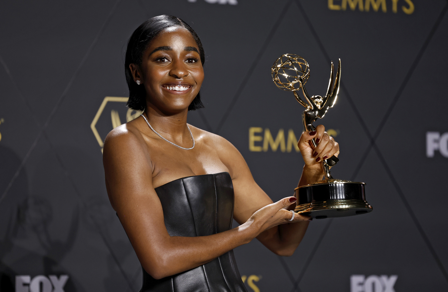 Ayo Edibiri smiles while posing with her Emmy Award.