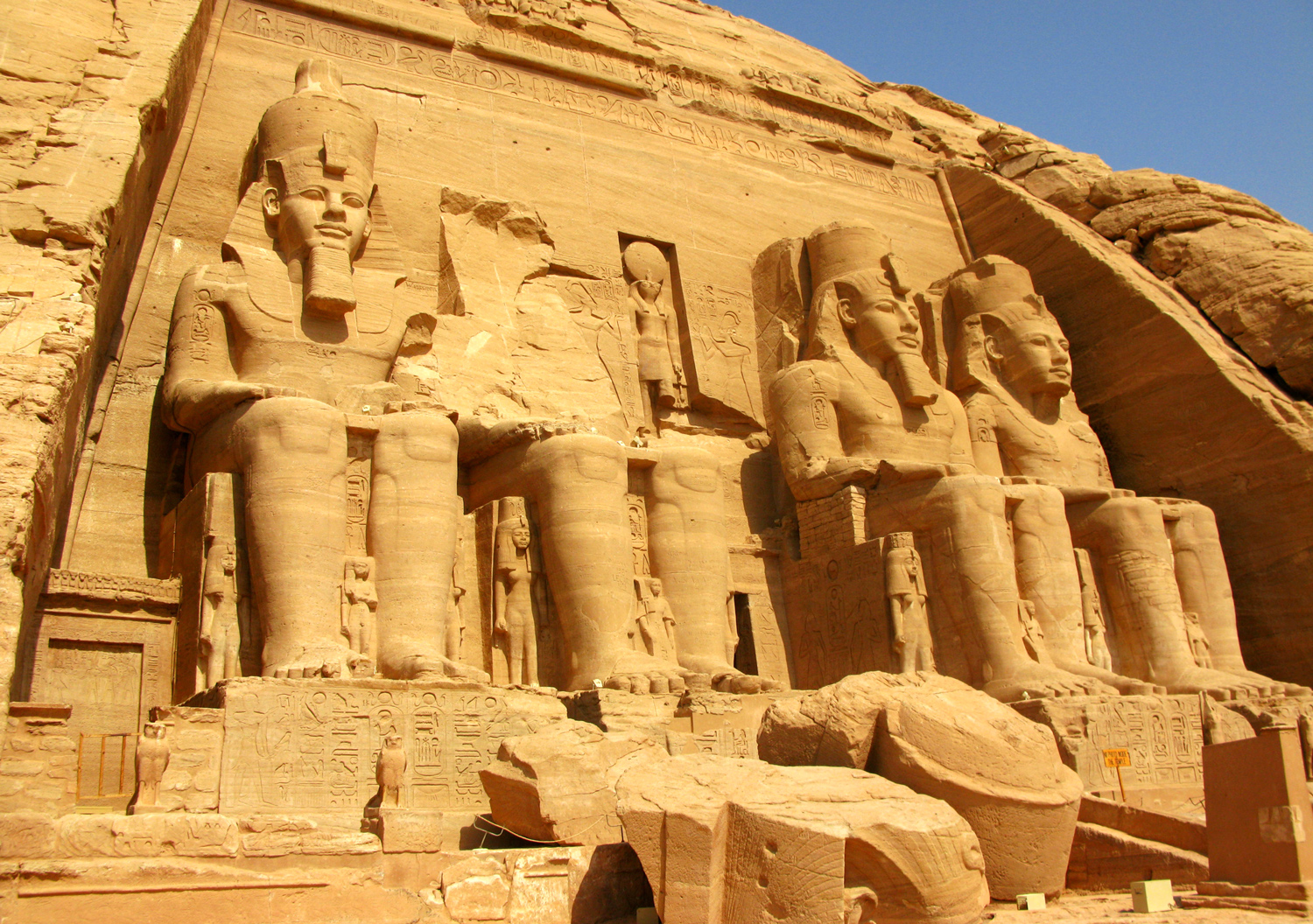 Four statues of a seated pharaoh are at the entrance to the temple of Ramses II.