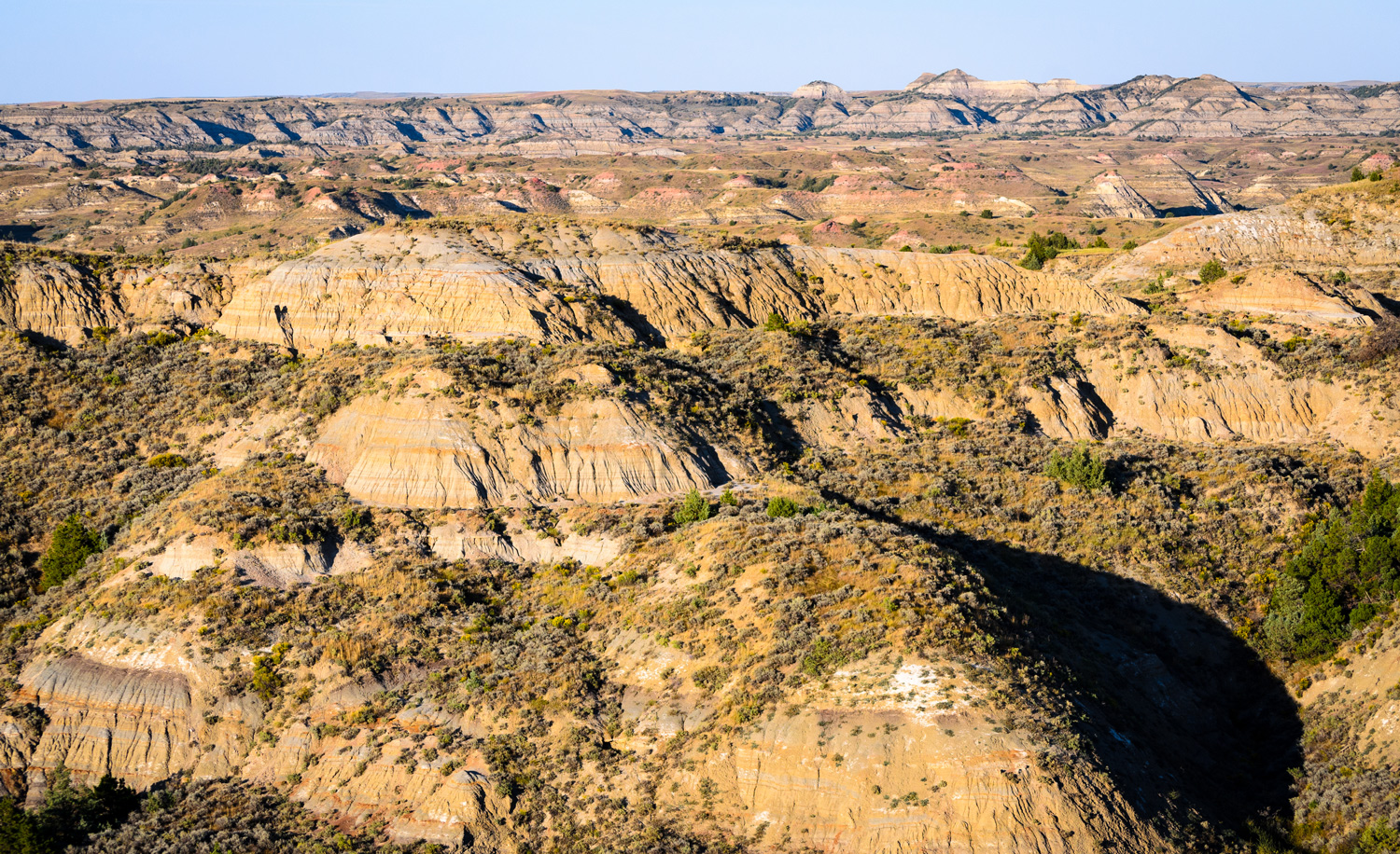 The Badlands of North Dakota, rocky landscape with some greenery, is shown.