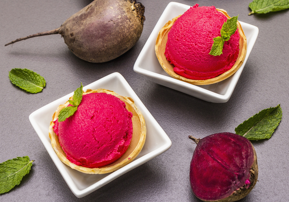 Two scoops of bright red ice cream are shown with two beets.