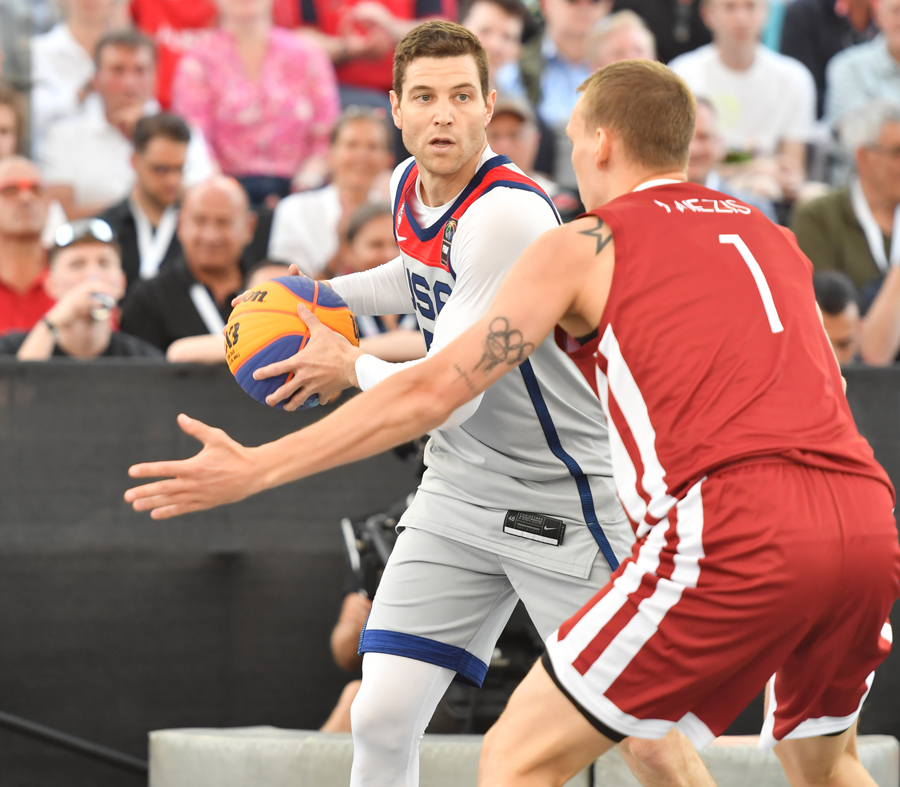 Jimmer Fredette holds the basketball as another player tries to block him.