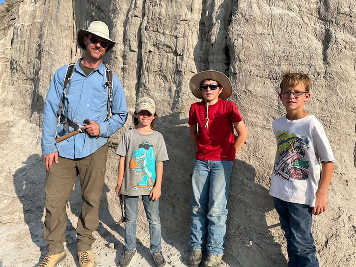 A man in a sun hat poses with three boys in the Badlands of North Dakota.