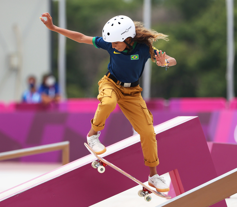 Rayssa Leal wears a shirt with a Brazilian flag as she balances on a skateboard that is on a ramp.