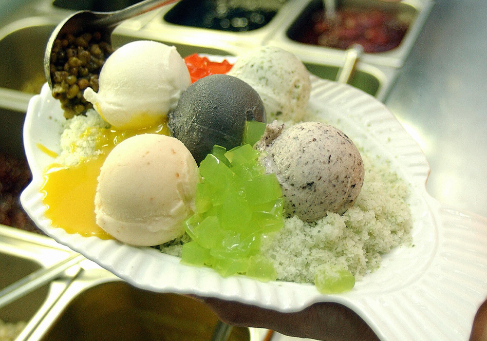 Four scoops of different ice cream flavors are on a plate with some garnishes.