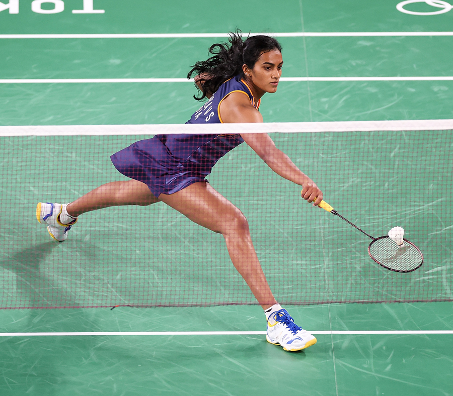 PV Sindhu is about to hit a badminton birdie on a badminton court.