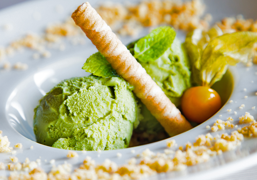 A bowl of green ice cream is garnished with a wafer.