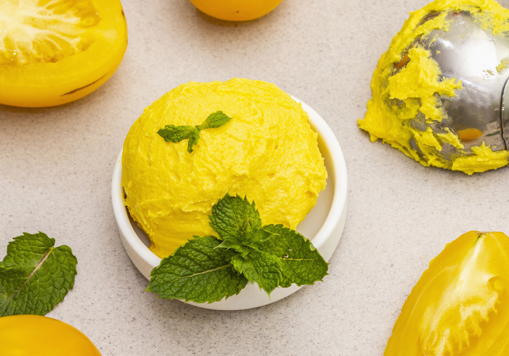 A scoop of yellow ice cream is garnished with mint leaves.