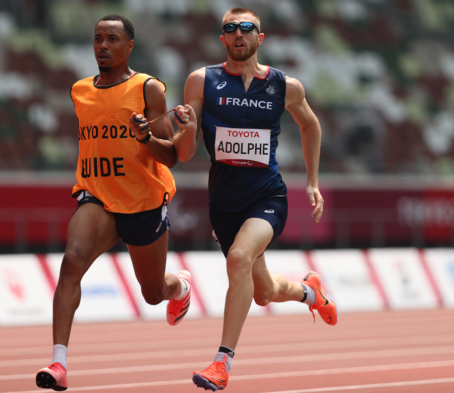 Timotheé Adolphe races on a track next to another runner.