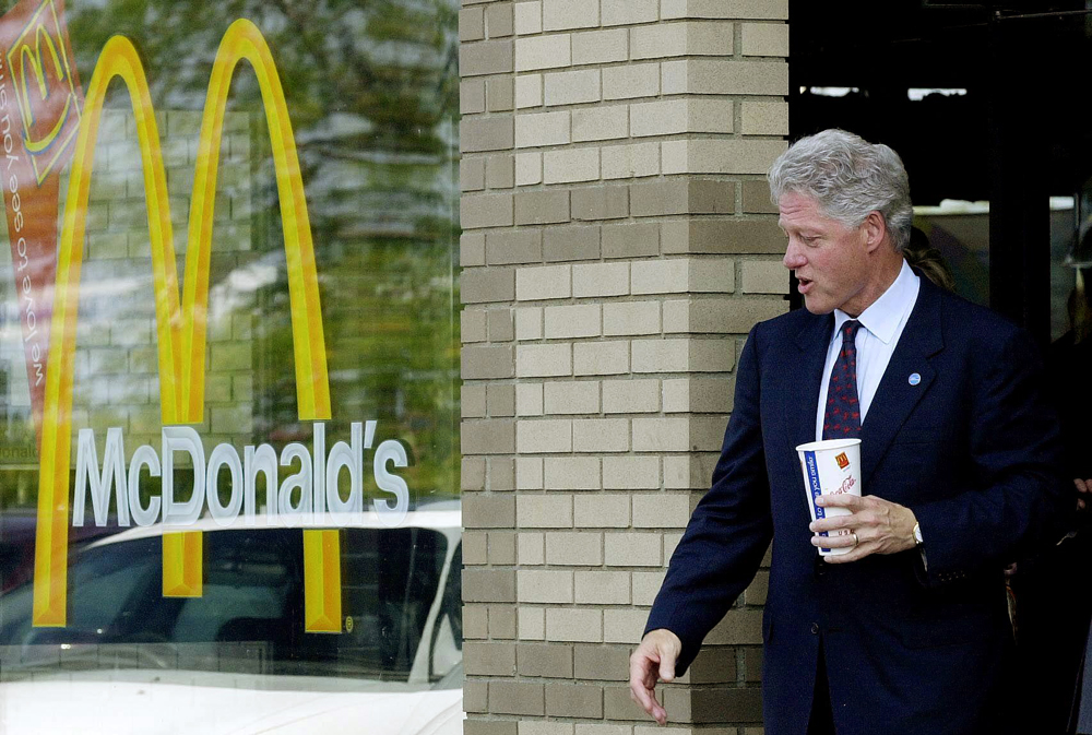 A photo of Bill Clinton leaving a McDonald’s holding a McDonald’s beverage.