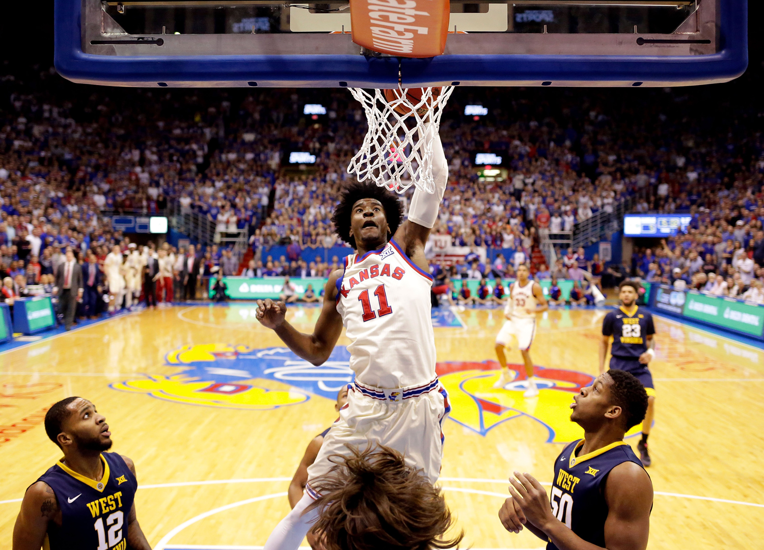 Josh Jackson dunks during a basketball game as opposing players surround the basket.