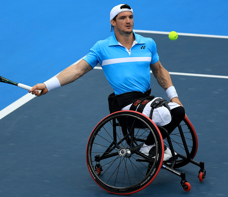 Gustavo Fernandez has his eyes on a tennis ball that is in the air as he is poised to hit it with his racket.