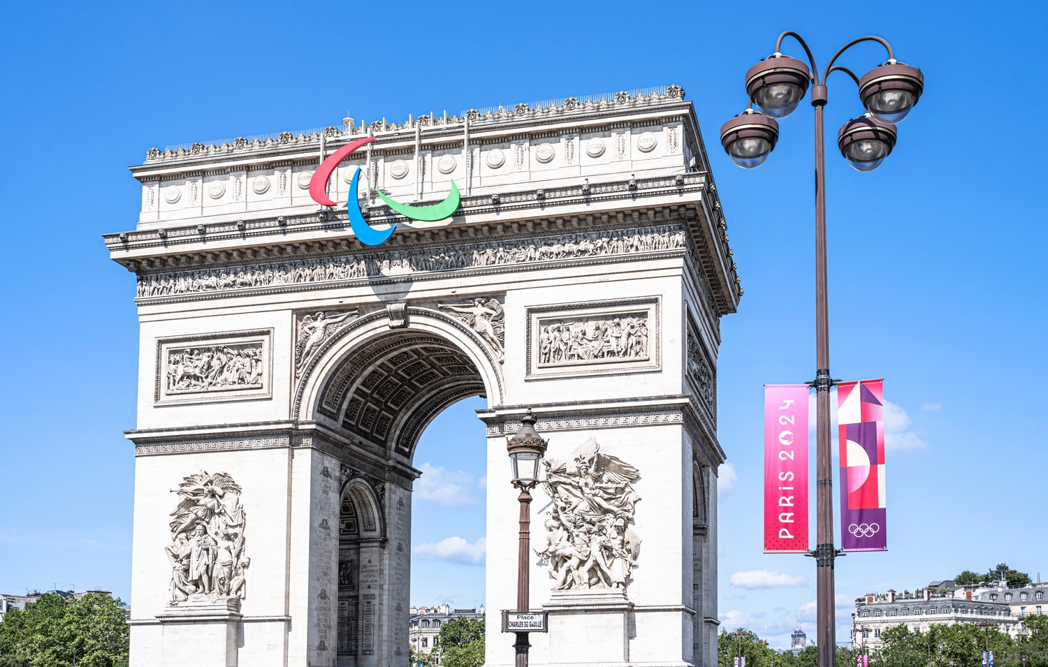 The Paralympics logo is displayed on the Arc de Triomphe in Paris, which is next to a banner that reads Paris 2024.