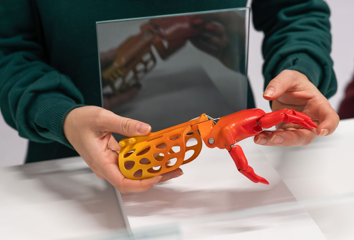 A woman holds a red prosthetic hand.