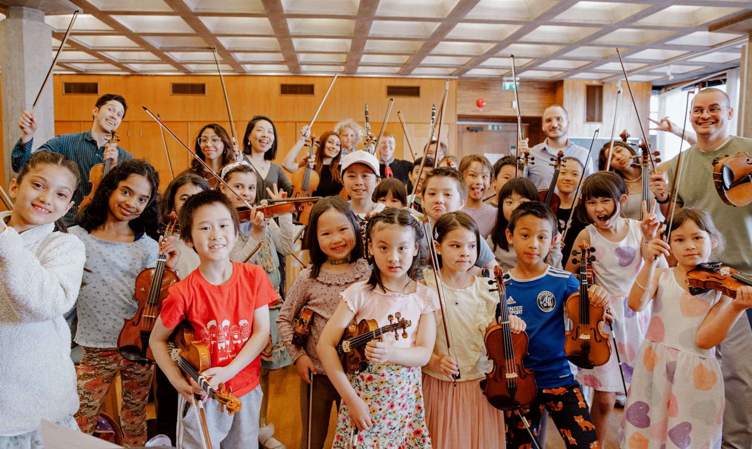 Ron Alvaraz and a group of children, teens, and young adults pose with their instruments.