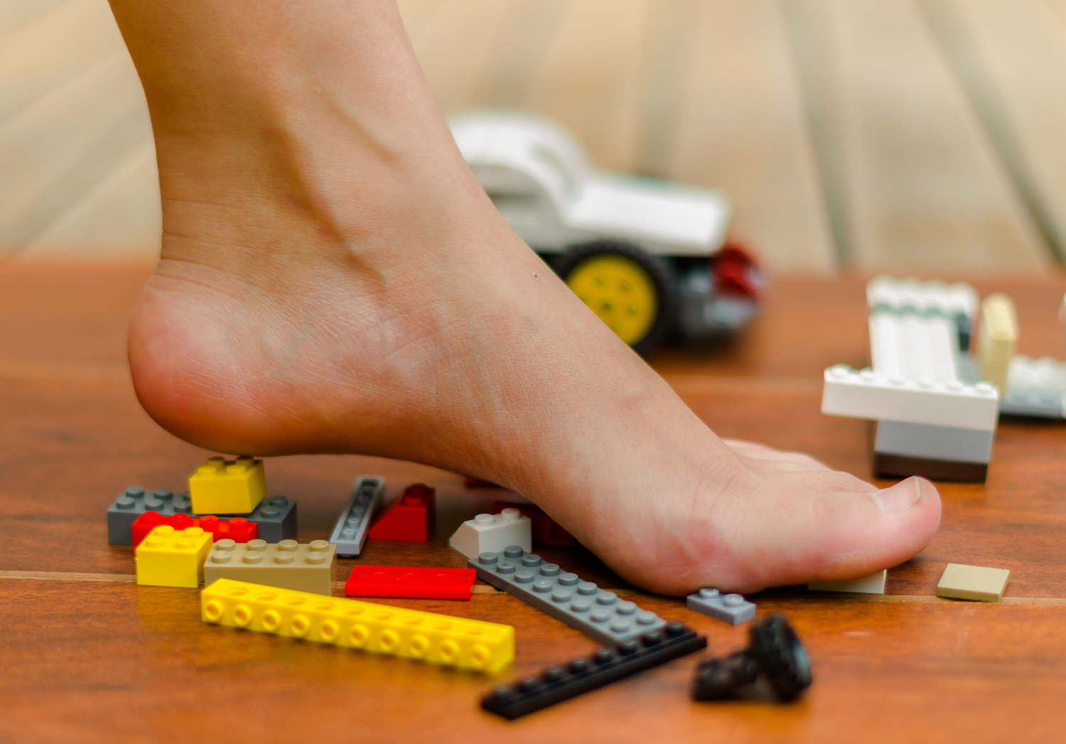 A bare foot steps on several Lego bricks at once.