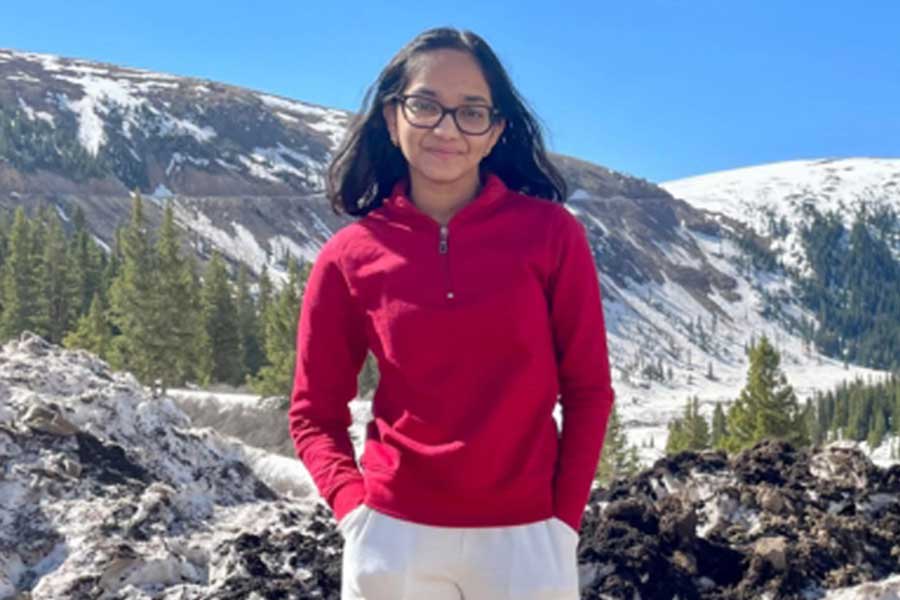 A teen stands in front of snowy mountains.