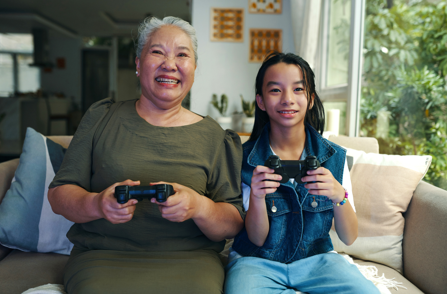 An older woman and a young girl play a video game together.