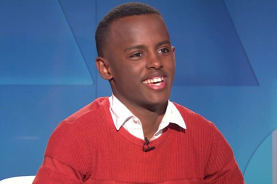 A smiling teen sits in a TV studio.