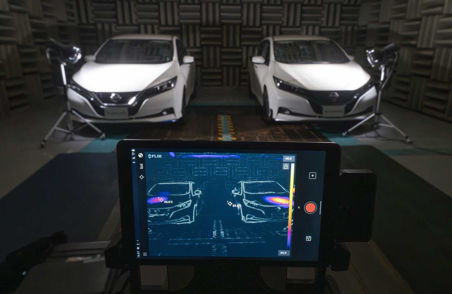 Heat lamps are pointed at two cars as a computer measures the cars’ temperatures.