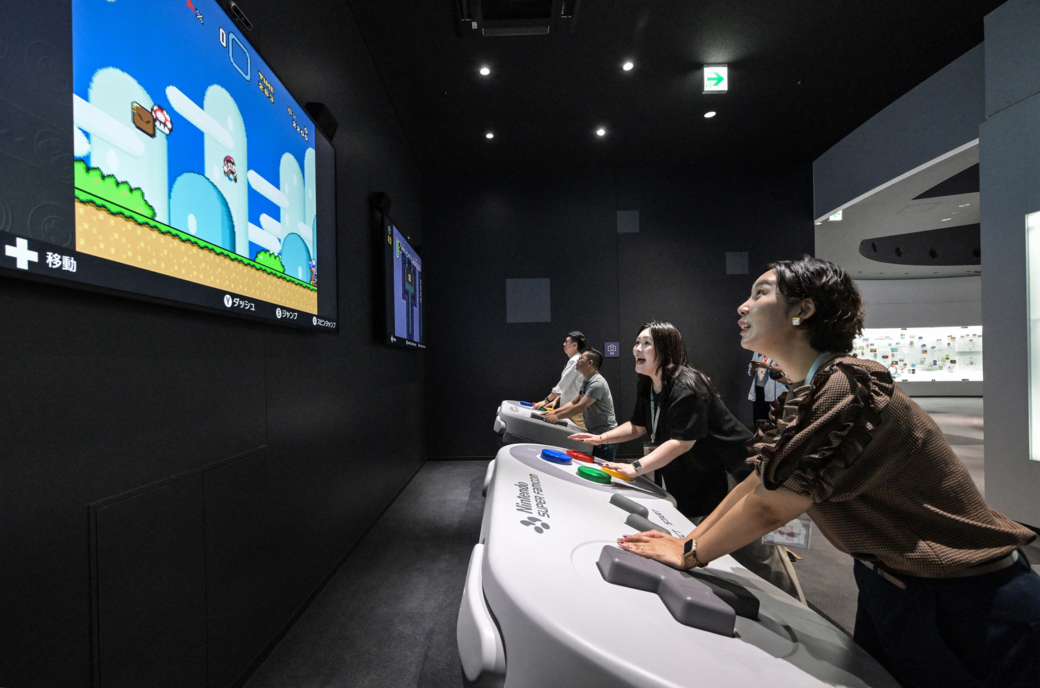 Four people play video games using giant controllers.