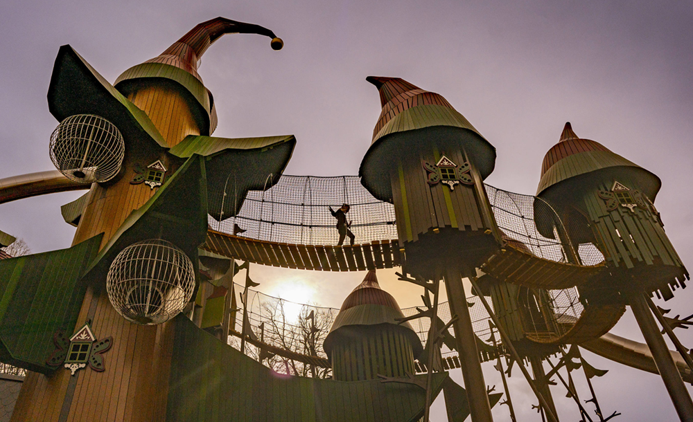 View from below showing a child walking across one of the bridges in a large play structure.