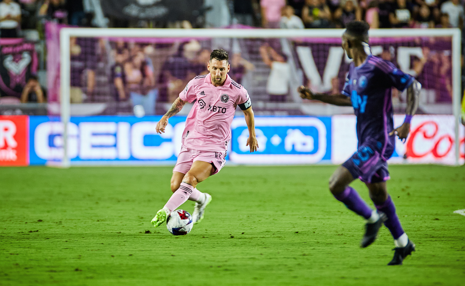 Lionel Messi dribbles the ball on the field as an opposing player looks to steal.