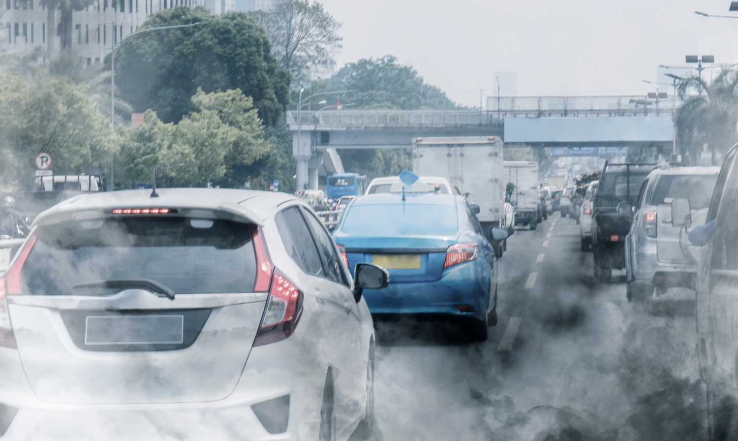 Exhaust is emitted from cars on a busy road.