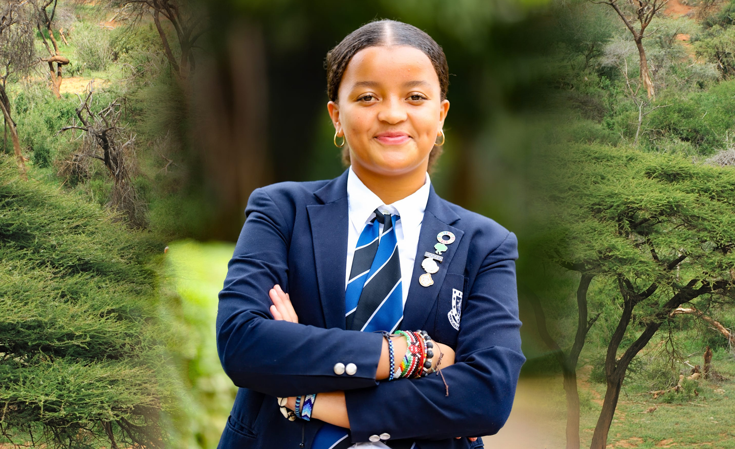 Ellyanne Wanjiku Chlystun stands outdoors in a blue school uniform and smiles with her arms crossed.