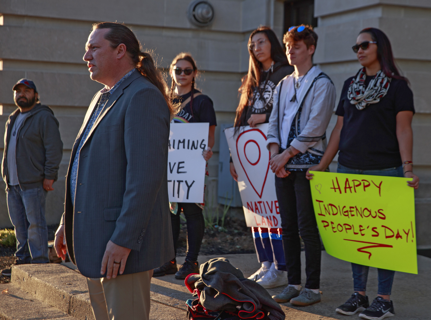 Ben Barnes speaks in front of a group of young people holding signs acknowledging Indigenous Peoples’ Day.