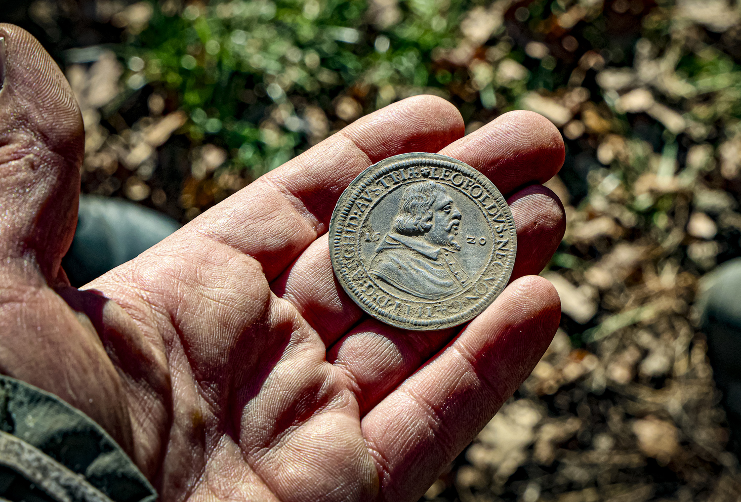 A coin with the year 1620 sits in the palm of someone’s hand.