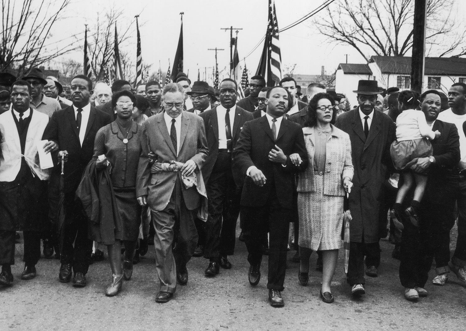 Martin Luther King has his arm linked with that of Coretta Scott King as they march along with other civil rights leaders.