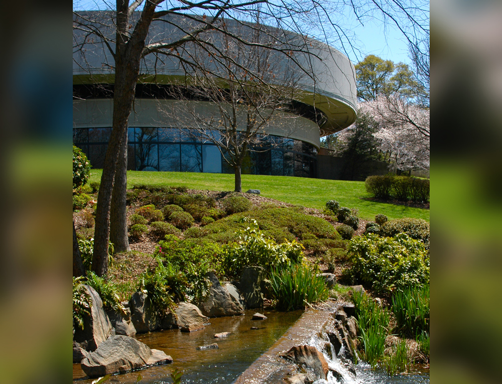 A round building with a pond and other landscape features.