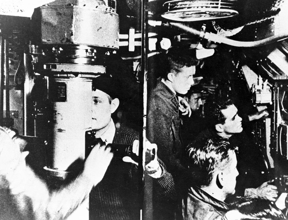 Jimmy Carter as a young man working in a submarine with several other young men.