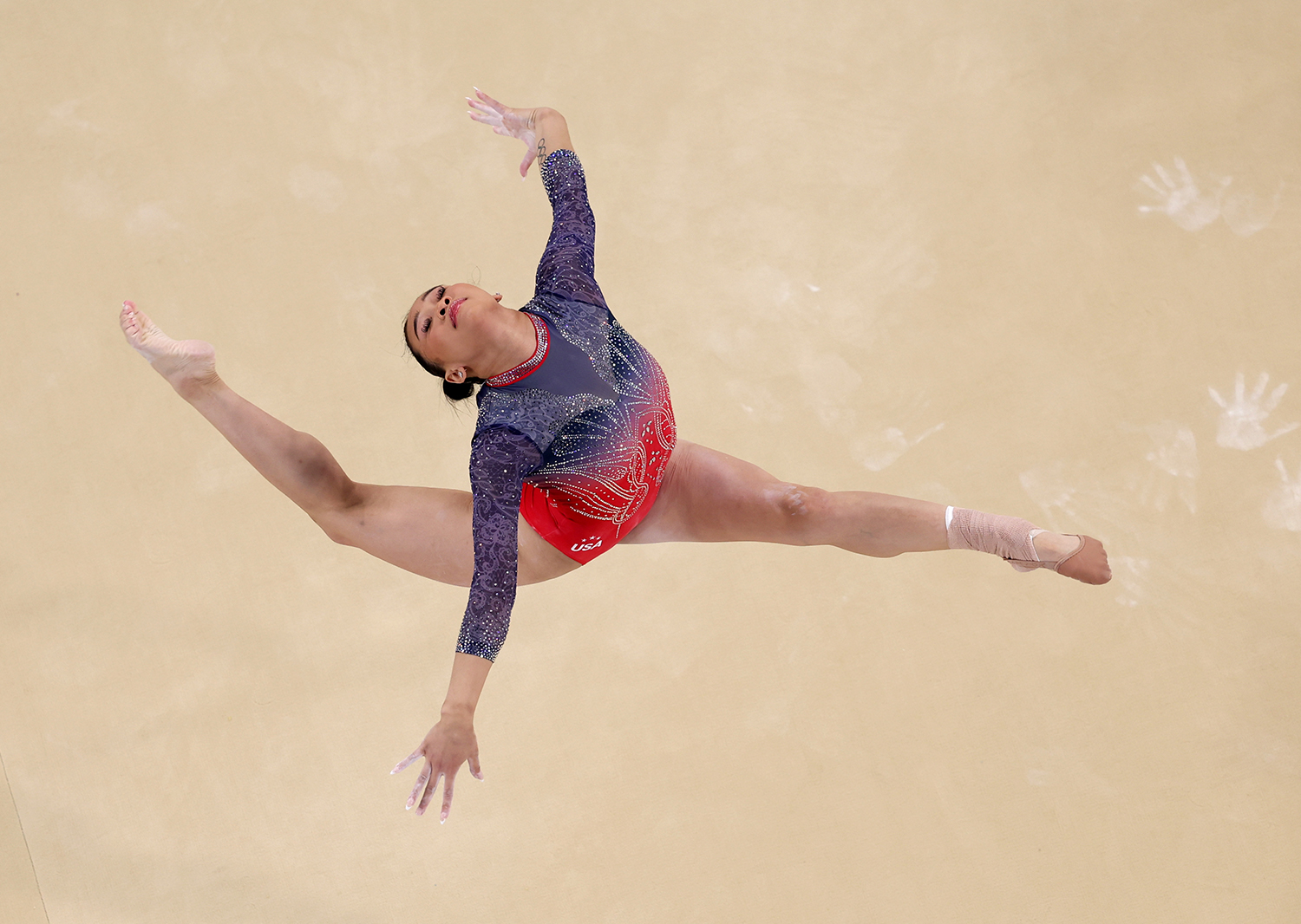 Suni Lee leaps and does a split during a floor exercise.