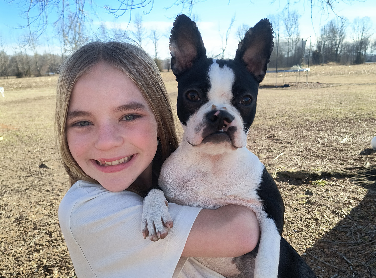 Kynlee Rogers holds a Boston terrier named Tennee and smiles.