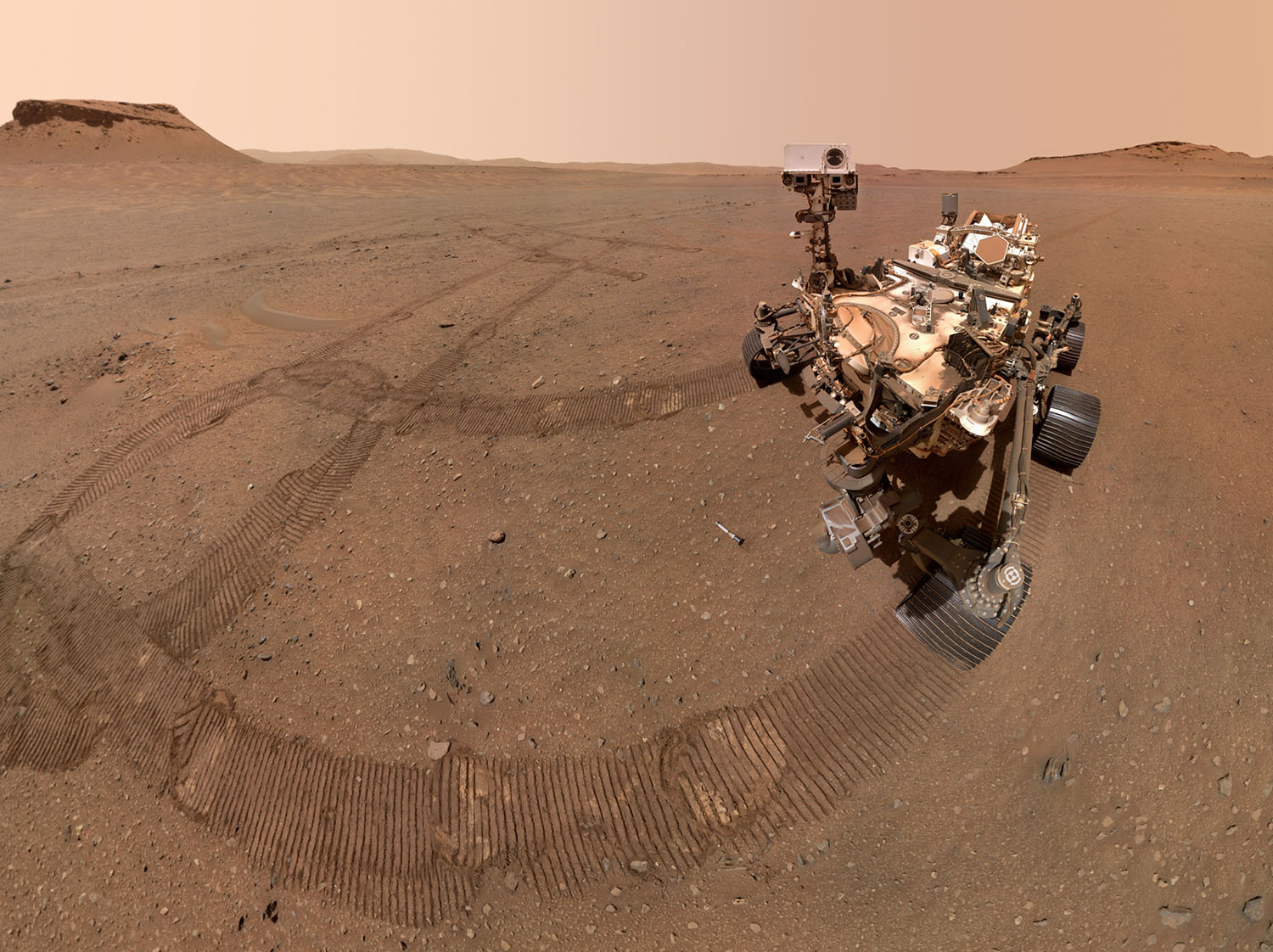 A rover is on the surface of Mars and its tracks are visible all around it.