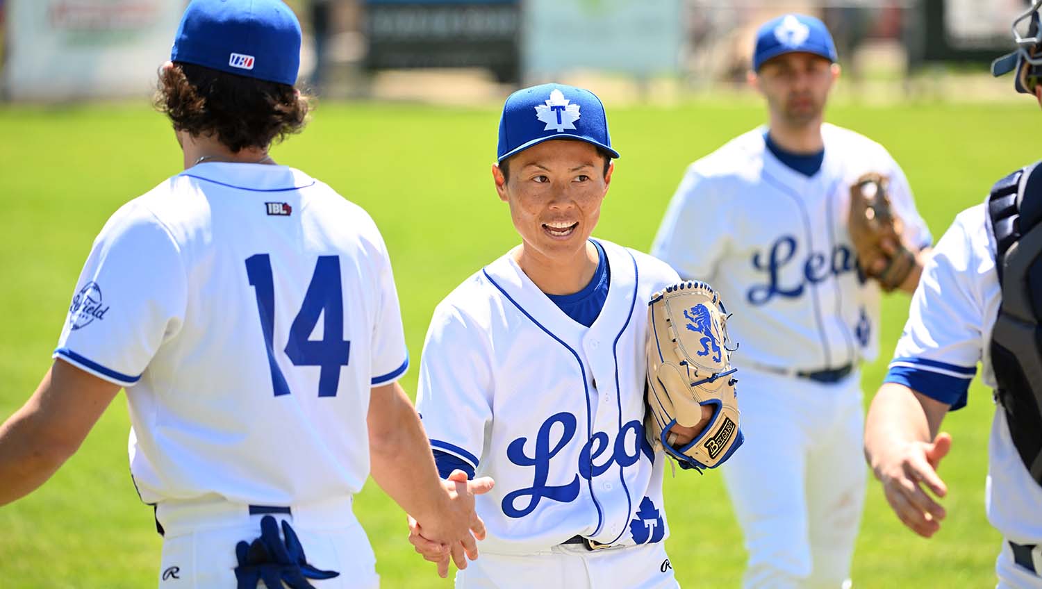 Ayami Sato smiles and shakes a teammate’s hand on the ballfield.