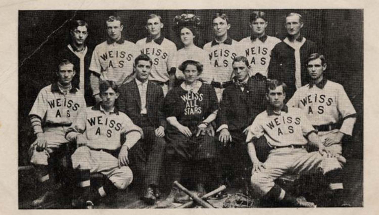 A group of men and one woman pose in a studio wearing baseball uniforms that read “Weiss AS.”