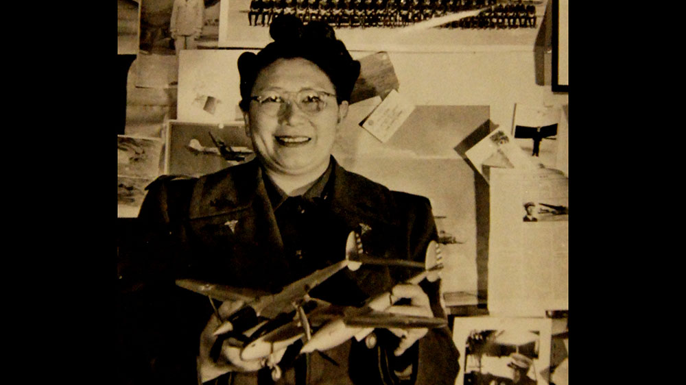 Margaret Chung smiles and poses with models of U.S. war planes.