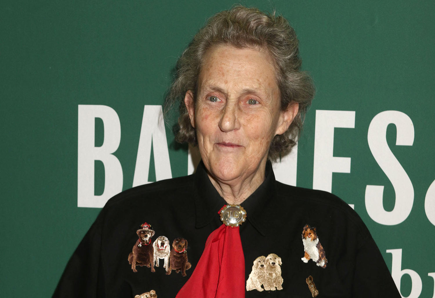 Temple Grandin poses in front of a green backdrop.