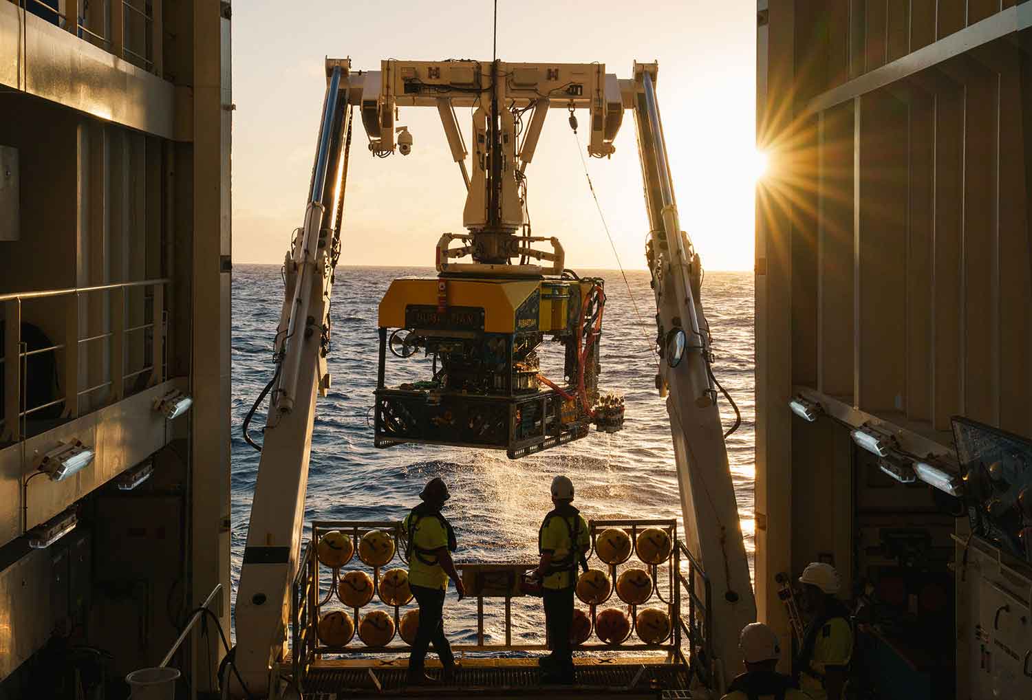 Equipment is used to bring a cube-shaped remote submersible out of the water and onto a ship.