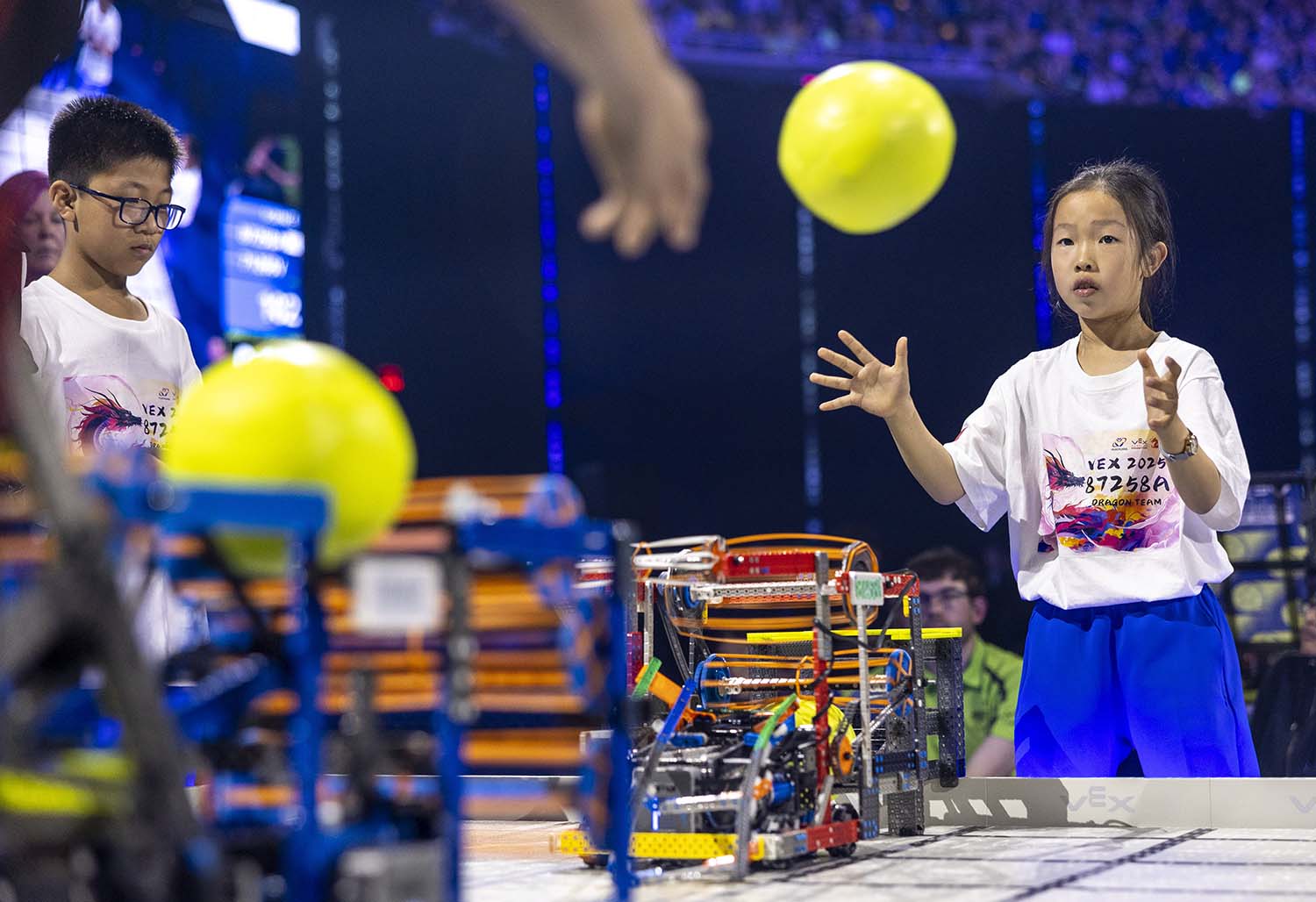 A young girl and boy stand at a table on which there is a small robot with circuits showing.