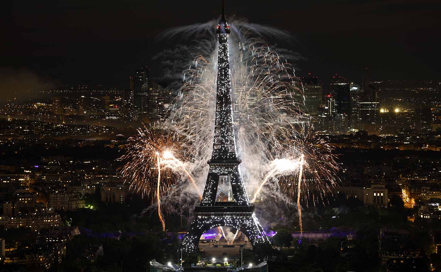 Fireworks are in the sky over and behind the Eiffel Tower.