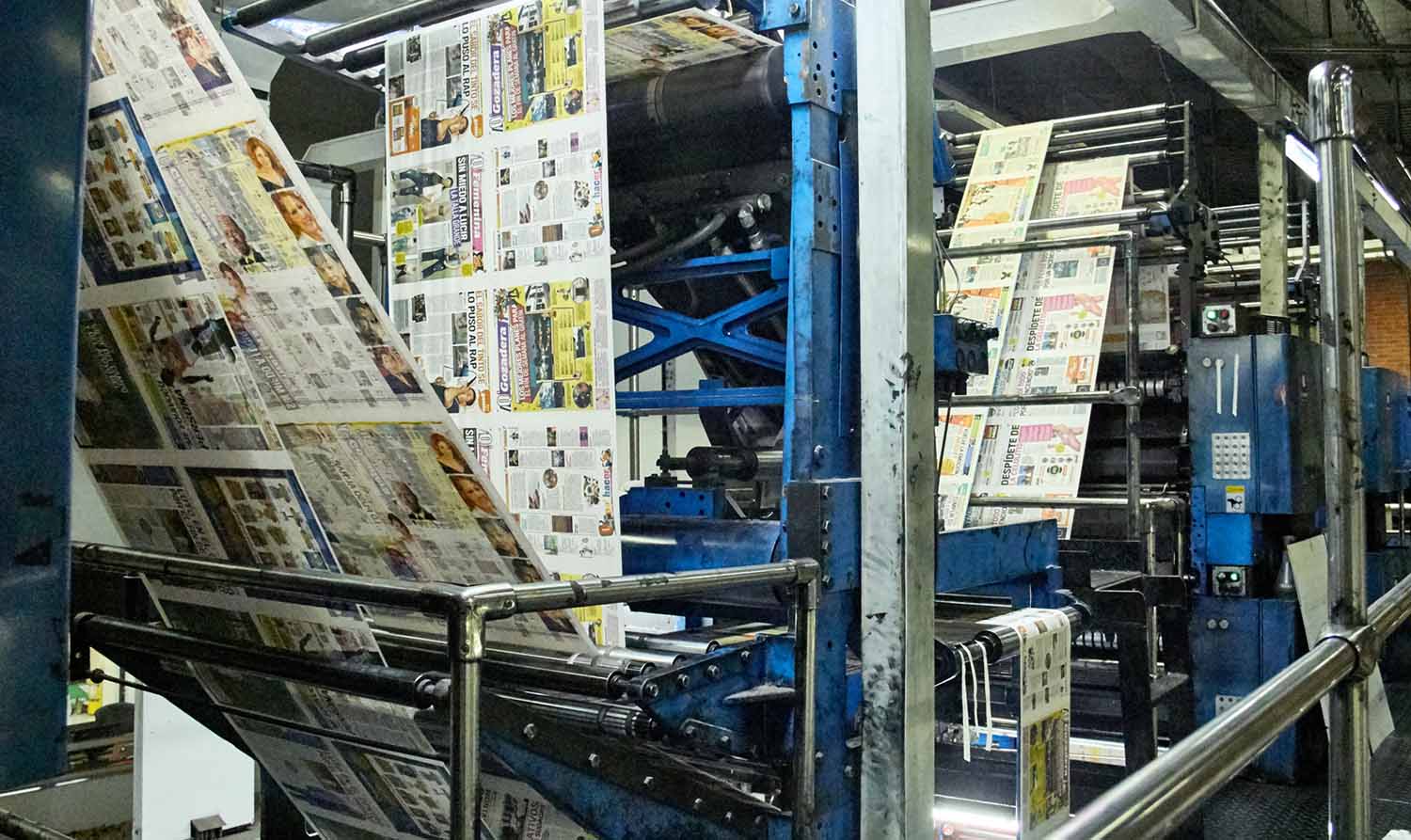 Pages of a newspaper are being produced by a printing press.