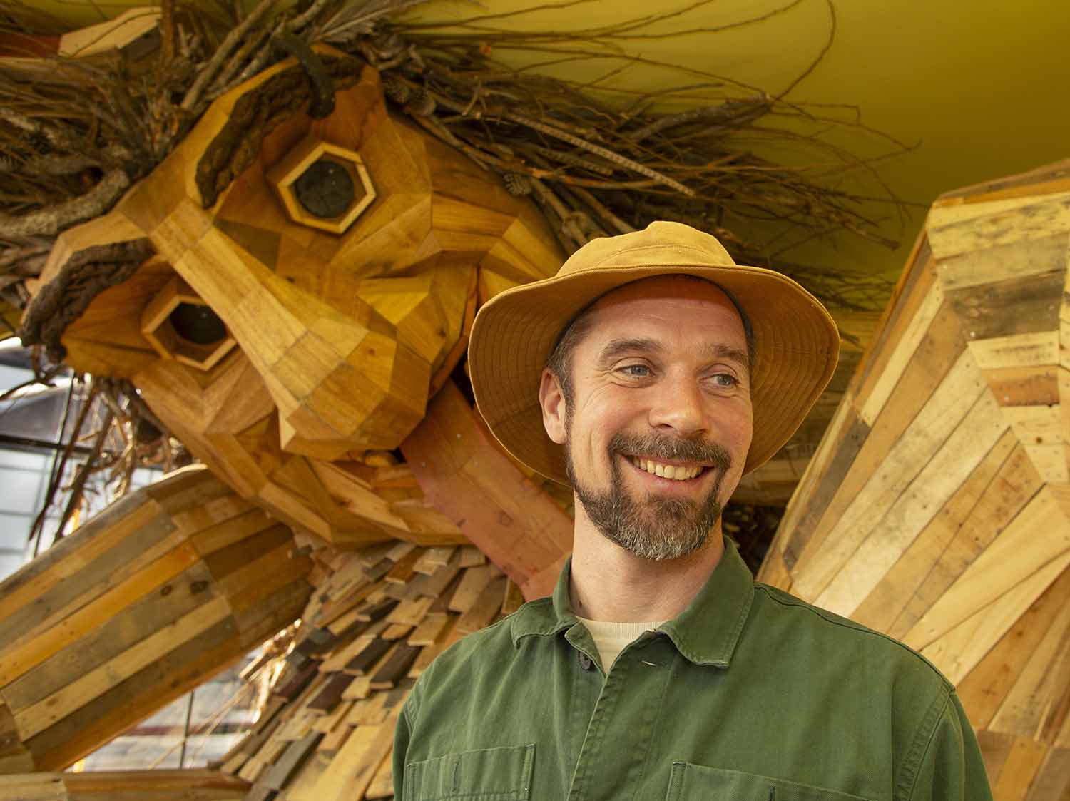 Thomas Dambo poses indoors in front of one of his wooden trolls.