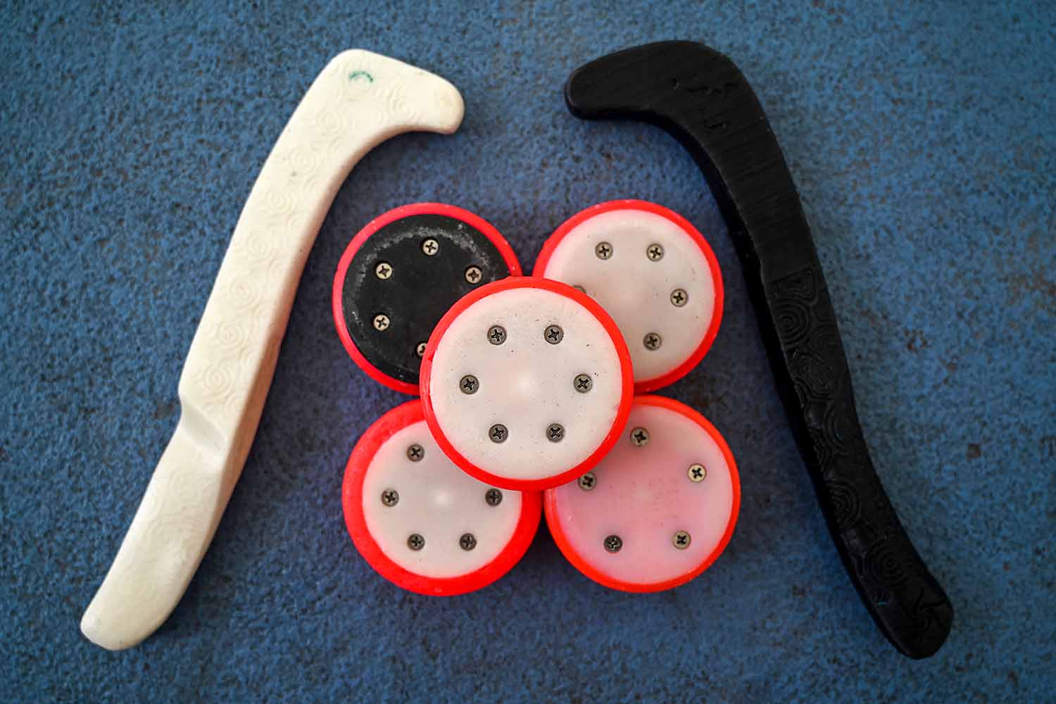 Two tiny hockey sticks are arranged around four hockey pucks.
