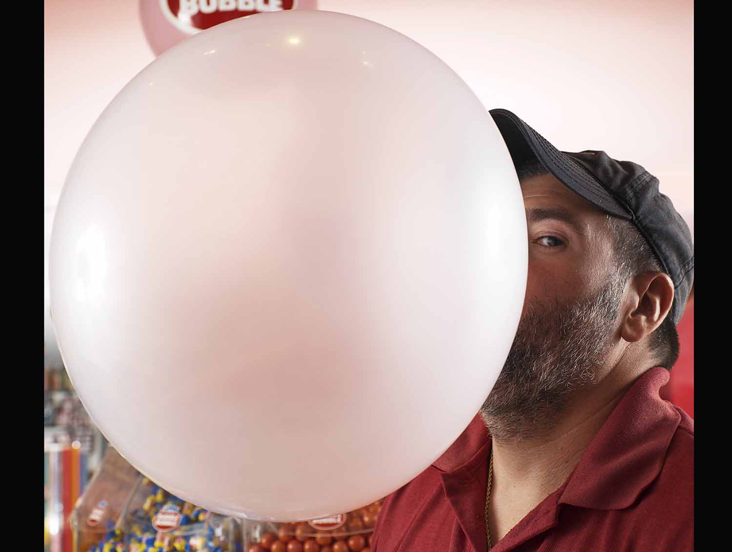 A man blows a bubblegum bubble that is much larger than his head